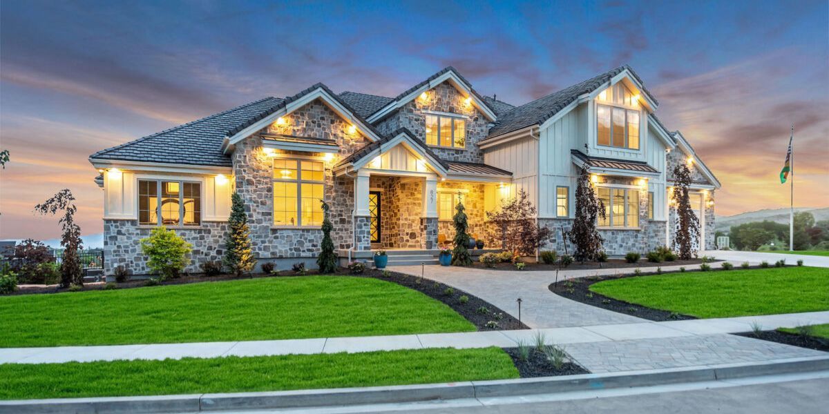 Luxury single-family home at dusk with stone exterior and landscaped yard, representing high-end residential homeownership.