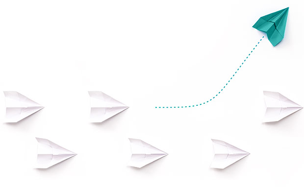 Independent mortgage broker standing out from the competition, represented by a green paper airplane veering away from a group of white paper airplanes.