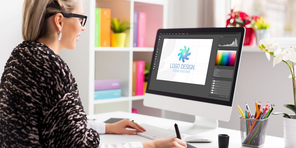 Graphic designer working on logo design for independent mortgage broker at a desk in front of her computer.